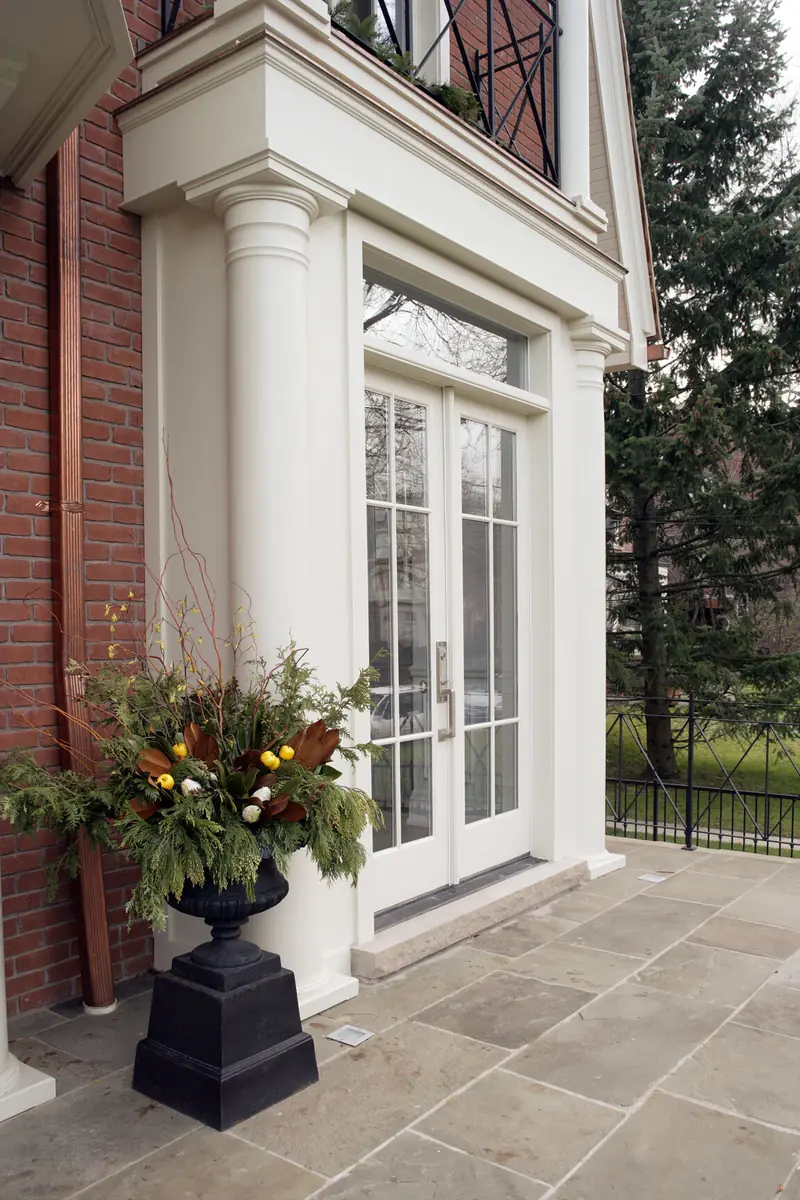 Brick house entrance with white columns, glass doors and planters
