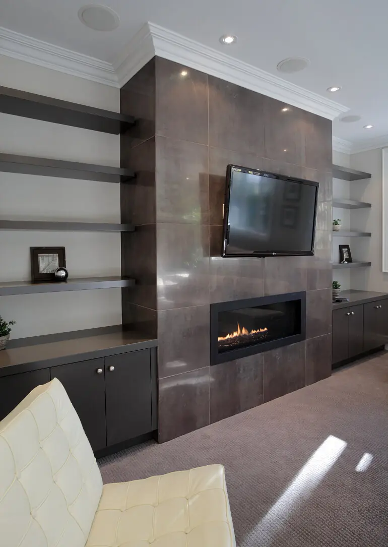 Dark stone fireplace feature wall with mounted television and built-in shelves