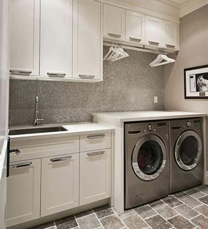 Laundry room with white cabinets, stacked-pair washer and dryer and patterned tile floor