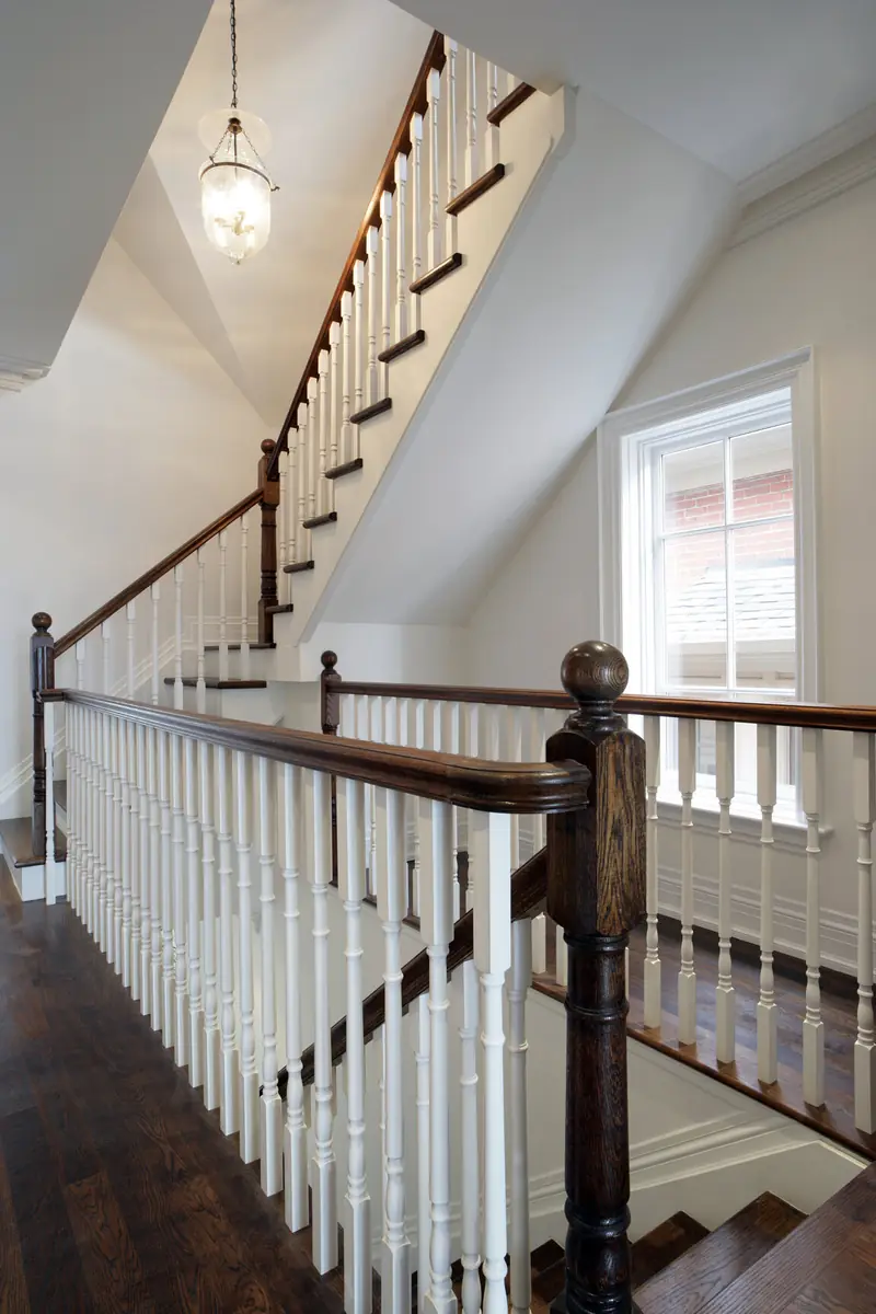 Three-storey staircase with white balusters and dark wood rail