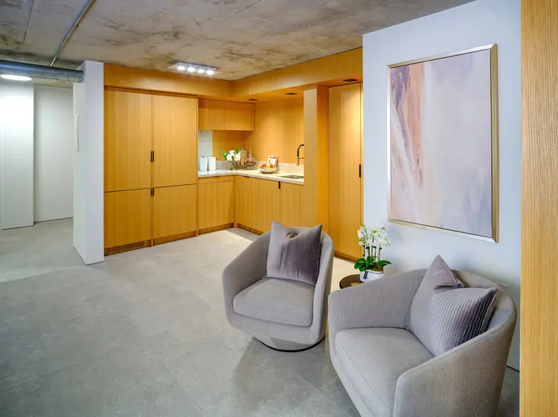 Inside Studio 955: lounge chairs, oak wardrobe wall and meeting table under a concrete ceiling